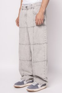 Lichtgrijze denim wijde broek met een patchworkontwerp en gestikte lijnen. Gepaard met grijs-witte sneakers voor contrast.