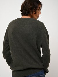 Dunkelgrüner Pullover in lässiger Passform, weichem Material, weitem Ausschnitt und gerippten Bündchen, von hinten betrachtet. Lässiger Stil mit minimalistischem Design.