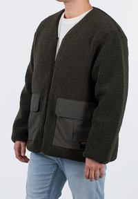 Zielona polarowa kurtka z zamkiem z przodu, dwiema dużymi kieszeniami i miękką fakturą. Posiada lekko luźny krój oraz prosty, okrągły kołnierzyk.