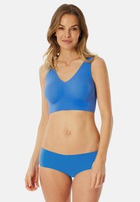Bralette bleu sans couture avec un design en V, associé à un short sans couture assorti. Texture lisse, couverture moyenne et style minimaliste.