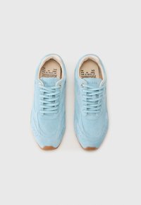 Light blue suede sneakers with round toes, textured upper, and flat laces. Features a gum rubber sole and printed interior label.