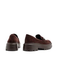 Pantofi slip-on din suede maro cu talpă din cauciuc masiv. Prezintă o textură netedă și o curea decorativă pe partea superioară. Design cu profil redus.