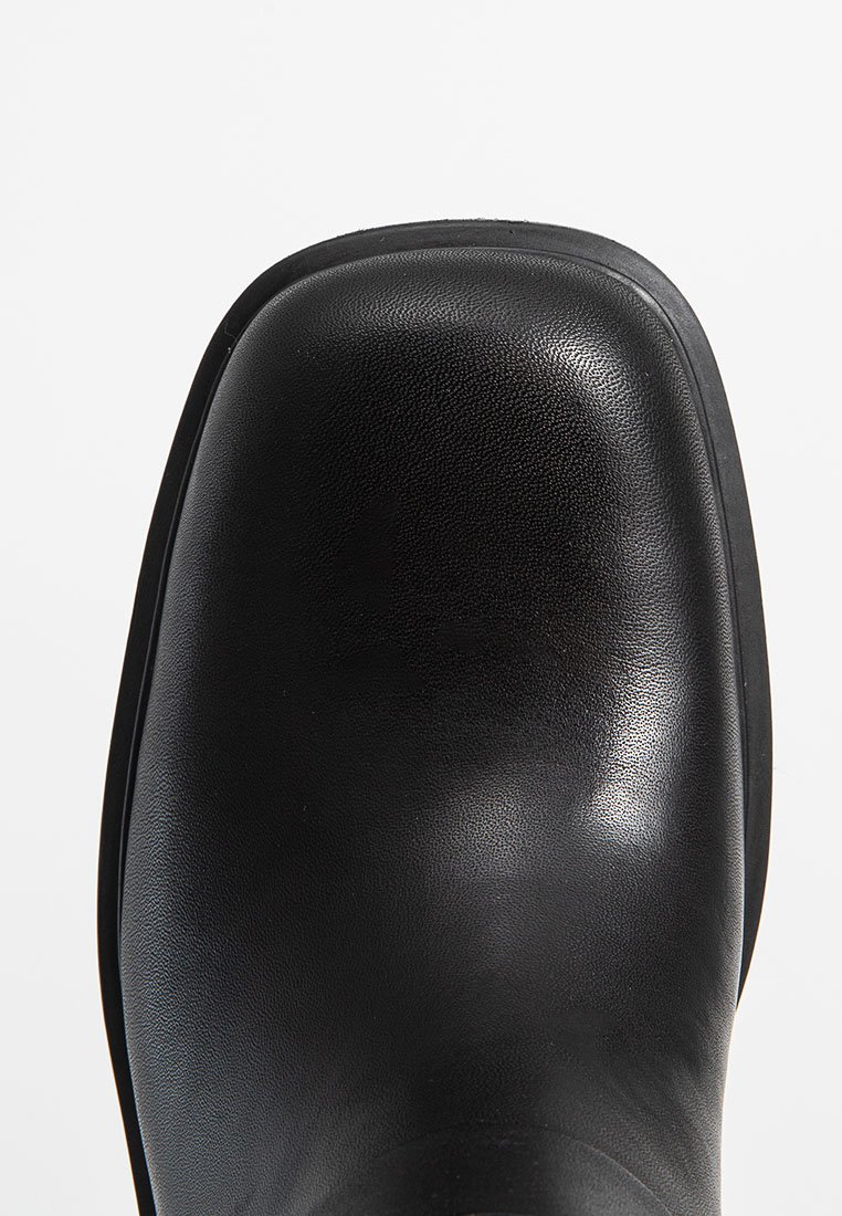 Schwarzer Lederstiefel mit runder Zehenform, strukturiertem Obermaterial und glatter Oberfläche. Gummisohle und minimale Nähte.