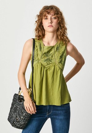 Top verde sin mangas con diseño floral bordado y textura plisada, combinado con jeans azul oscuro y un bolso negro tejido.