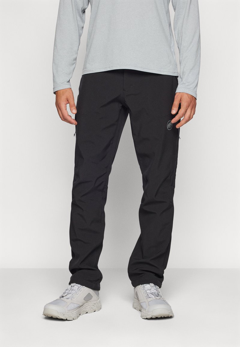 Schwarze Outdoor-Hosen aus strapazierfähigem, leichtem Material; ausgestattet mit Cargo-Taschen und einem Logo-Detail an der Seite. Kombiniert mit einem grauen Langarmhemd.