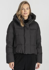 Czarna kurtka puchowa z wysokim kołnierzem, kapturem i pikowanym wzorem. Zamek błyskawiczny i szerokie rękawy podkreślają jej funkcjonalny styl.