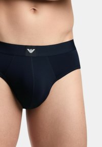 Granatowe slipy o dopasowanym kroju. Wykonane z gładkiej tkaniny z elastycznym pasem logo. Centralny szew dla dodatkowego wsparcia.