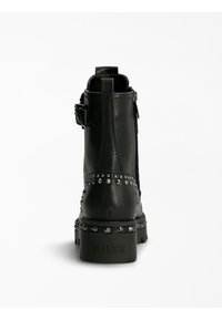 Stivali alla caviglia in pelle nera con decorazioni in borchie e zip laterale. Presentano un piccolo dettaglio a fibbia e una suola in gomma testo con branding.