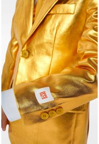 Kuldne metallik ülikonnajakke sillerdava tekstuuriga, millel on silt "OPPO SUITS" ja kolm kollast nööpi varruka peal.