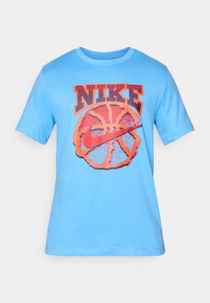 Vaaleansininen puuvillapaita, jossa on iso oranssi Nike-logo koripallokuvan päällä, lyhyet hihat ja pyöreä kaula-aukko.
