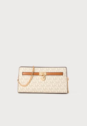 Pochette en toile blanche avec motif logo MK, accent en cuir marron, quincaillerie dorée et bandoulière en chaîne. Forme rectangulaire avec texture lisse.