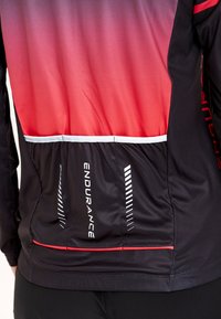 Svart atletisk jacka med en gradientdesign i röd och lila, reflekterande detaljer och en bakficka märkt "ENDURANCE." Slät textur.