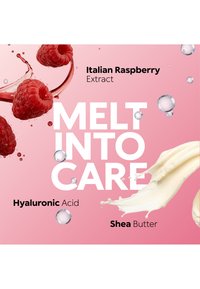Framboises avec éclaboussure de liquide, tourbillon de crème et texte mettant en avant l'extrait de framboise italienne, l'acide hyaluronique et le beurre de karité sur fond rose.