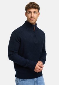Marineblå strikket sweater med høj krave og halv lynlås design. Har ribbede manchetter og kant. Blød tekstur, afslappet pasform.