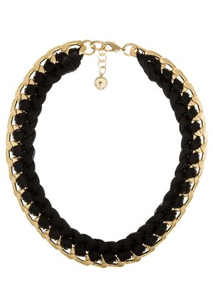 Collier chaîne en or entrelacé avec un tissu noir épais tressé et une petite étiquette ronde en or pour la fermeture.