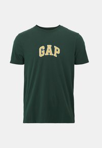 Camiseta de manga corta de color verde oscuro con cuello redondo, con letras "GAP" en amarillo y blanco centradas en el pecho.