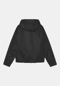 Zwarte, capuchonjas gemaakt van glanzende, lichte stof. Kenmerkt zich door elastische manchetten en zoom, met een eenvoudig, strak ontwerp en zonder zichtbare bevestigingsmiddelen.