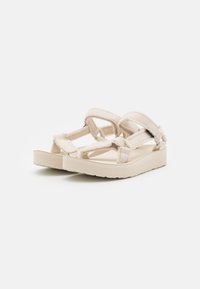 Light beige platform sandals with cross-strap design. Soft fabric straps and textured insole for comfort. Thick rubber sole.