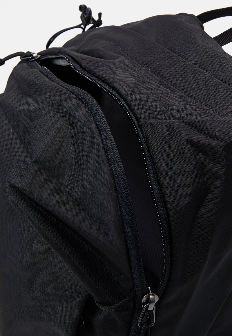 Zaino nero con un tessuto testurizzato, tasca con zip e chiusura con cordoncino regolabile sulla parte superiore. Design durevole e funzionale.