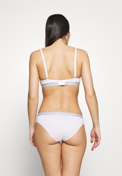 White cotton bra and panty set with adjustable straps and an elastic waistband featuring "Emporio Armani" logo in gray. Smooth texture.