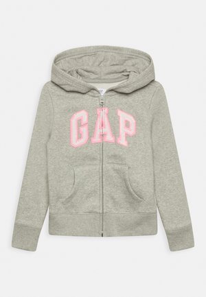 Sweat à capuche zippé gris clair avec capuche et poches avant, avec de grandes lettres roses en contour « GAP » sur la poitrine.