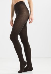Bruine ondoorzichtige panty's gemaakt van een zacht materiaal, met een hoge tailleband en een gladde, gelijkmatige textuur die tot de teen reikt.