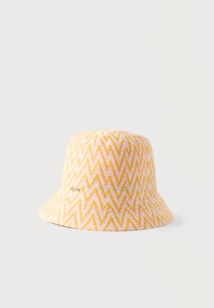 Sombrero tipo cubo con patrón de zigzag amarillo y rosa, con una pequeña etiqueta rectangular de la marca en un costado, sobre un fondo claro y liso.