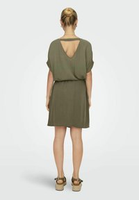 Olivgrünes Kleid mit lässiger Passform, kurzen Ärmeln und tiefem V-Rücken. Hergestellt aus leichtem Material, mit einem gerafften Taillenbereich und glatter Textur.