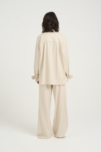 Chemise beige surdimensionnée et pantalon large en tissu doux et léger ; dotés de poignets à boutons et d'une coupe décontractée.
