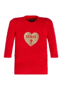 Czerwony sweter z dzianiny, z rękawami o długości trzech czwartych. Posiada teksturowany wzór oraz złotą naszywkę w kształcie serca z napisem "GUESS ?" na środku.