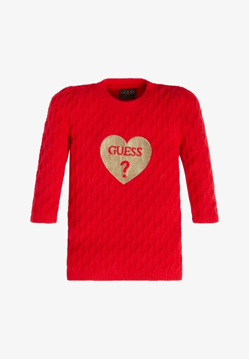 Czerwony sweter z dzianiny, z rękawami o długości trzech czwartych. Posiada teksturowany wzór oraz złotą naszywkę w kształcie serca z napisem "GUESS ?" na środku.