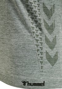 Lys grøn atletisk skjorte med tekstureret stof, prydet med mørkegrønne geometriske mønstre og "hummel"-logoet ved sømmen.