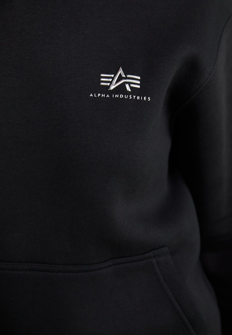 Felpa nera realizzata in tessuto misto cotone. Presenta un piccolo logo bianco e la scritta "ALPHA INDUSTRIES" nella parte superiore sinistra del petto.