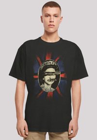 Black cotton t-shirt featuring a graphic print of a crowned figure against a faded Union Jack background with text "God Save The Queen."
