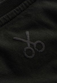 Zwarte stof met een subtiele, gestructureerde schaarlogo in een donkerdere tint zwart, geplaatst tegen een gladde, geribbelde ondergrond.