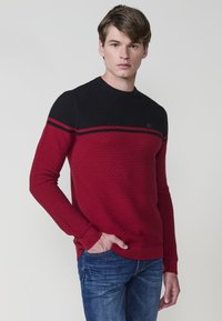 Maglione texturizzato rosso e nero con scollatura rotonda, caratterizzato da un motivo a righe orizzontali e polsini e fondo a costine.