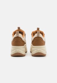 Sneaker marroni e crema con retro texturizzato, colletto imbottito e suola in gomma. Presenta una linguetta con marchio e accenti a coste.