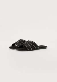 Sandale negre cu curele țesute, având accente metalice argintii, talpă plată și design cu vârful deschis. Material moale, cu textură.