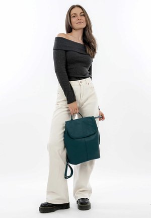 Zaino in pelle color teal con chiusura a pattina, dotato di spallacci regolabili. La borsa ha una texture liscia e una forma strutturata, adatta per un uso quotidiano.