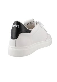 Zapatilla blanca con parte superior de cuero suave, acento negro en el talón, punta redonda y suela de goma texturizada. Marca visible en el talón.