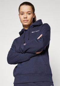 Felpa con cappuccio colore blu navy in morbido cotone, dotata di tasca frontale, logo ricamato e cappuccio con cordino regolabile.