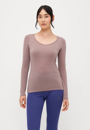 Top a maniche lunghe, con scollo a barca, in tessuto mauve tenue, design aderente, texture liscia. Abbinato a leggings blu con dettagli del logo.