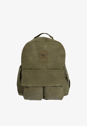Oliwkowo-zielony plecak Adidas z górnym uchwytem, przednią kieszenią z klapką, dwoma dolnymi kieszeniami z przodu oraz naszywką z logo umieszczoną nad klapką.