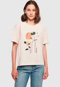 Tricou din bumbac roz deschis, cu mâneci scurte, având un design floral în nuanțe de negru, portocaliu și crem, și un decolteu rotund.