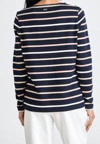 Chemise rayée à manches longues navy avec des rayures rose pâle, blanche et beige. Tissu doux avec une coupe décontractée et un col rond. Petit détail d'étiquette au dos.