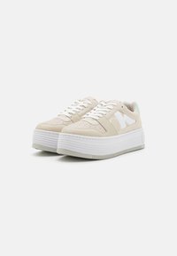 Sneakers platform beige con lacci bianchi e suola in gomma testurizzata. Presentano una tomaia in pelle e un accento verde menta sul tallone.