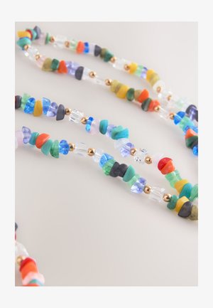 Daugiasluoksnis vėrinys iš spalvotų karoliukų įvairių formų ir dydžių, pertraukiamas auksiniais akcentais ir skaidriais kristalais.