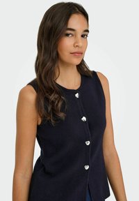 Marineblaues ärmelloses Strickoberteil mit Rundhalsausschnitt, das vorne mit herzförmigen silbernen Knöpfen versehen ist und einen lockeren Schnitt hat.
