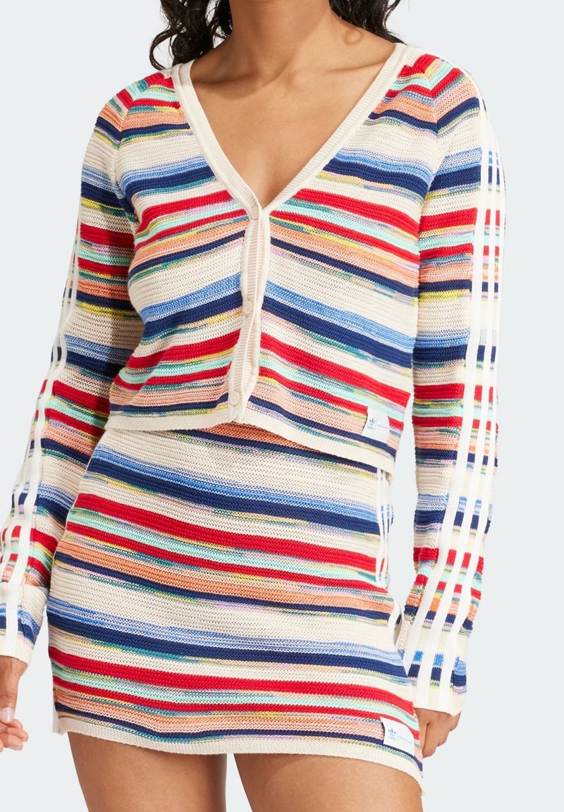 Conjunto de cárdigan de punto a rayas y falda corta en crema, rojo, azul y verde. Presenta cierre de botones y rayas laterales. Tela con textura y patrón.