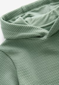 Tekstylizowany zielony hoodie z wzorem pikowanej diamentowej tkaniny, z dużym kapturem i miękkim, wygodnym materiałem.